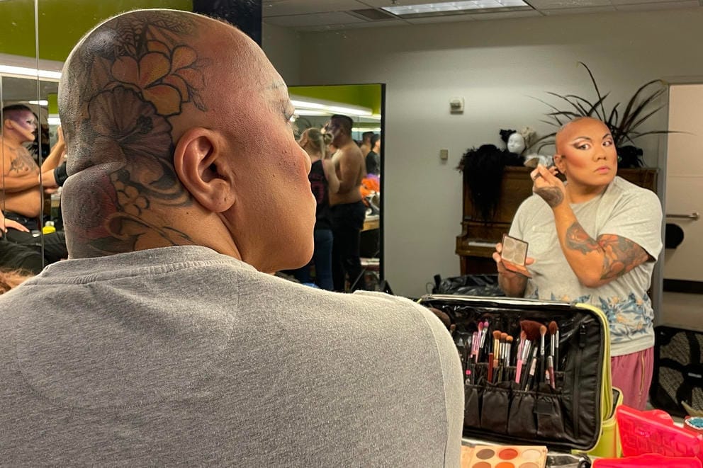 A performer does their makeup in a mirror