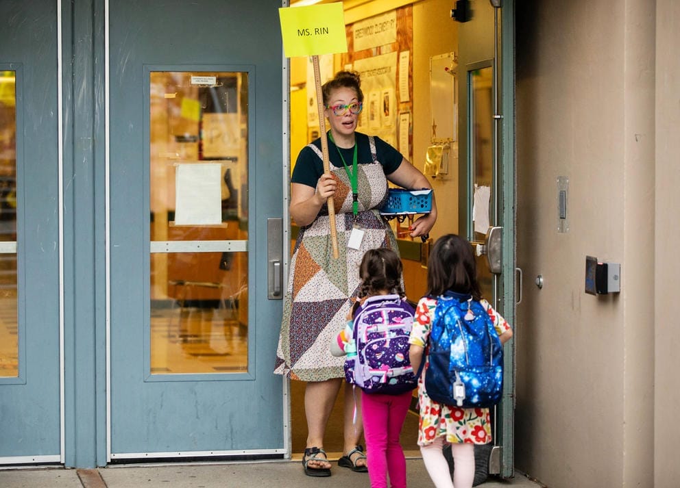 A teacher holding a sign that says