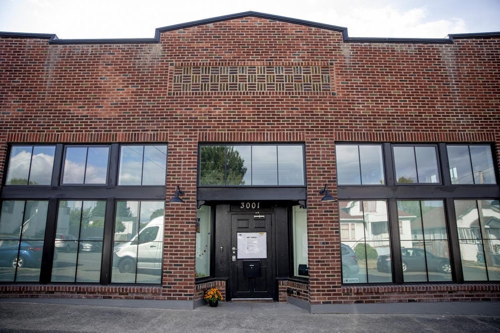 Brick building with six large windows, black door in the middle