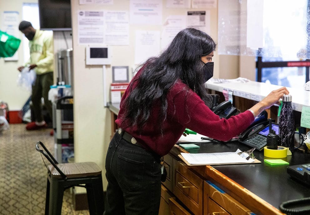 a woman stands behind a desk