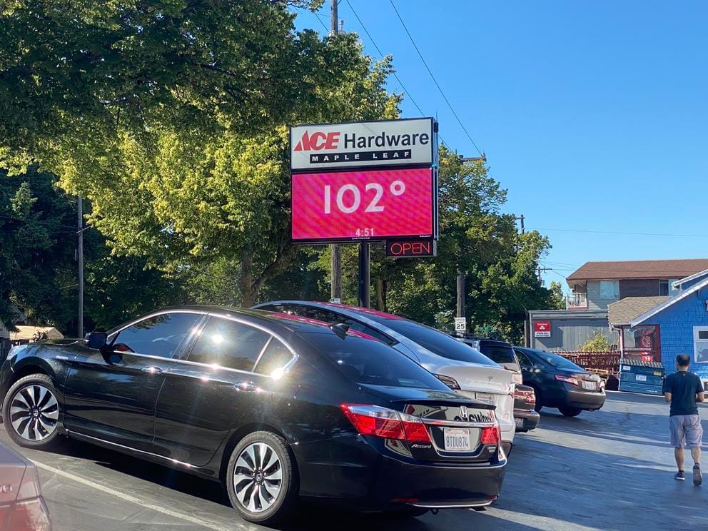 a sign showing the temperature outside a hardware store on a hot day