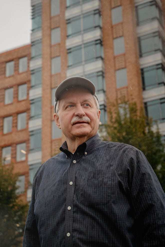 Man stands in front of tall brick building
