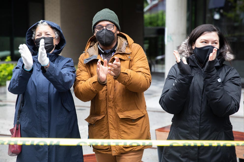 Three people stand behind yellow