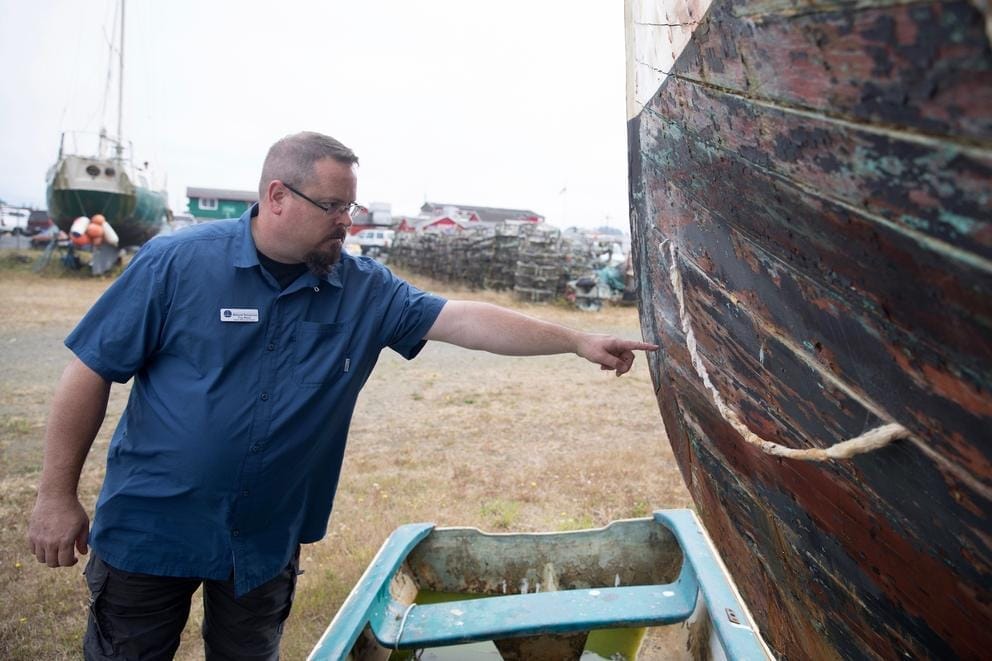 Troy Wood, derelict vessel removal program manager for the state Department of Natural Resources, points out damage on an aging wooden-hulled vessel that could be a “future customer” of a boat recycling center in Ilwaco, Washington.
