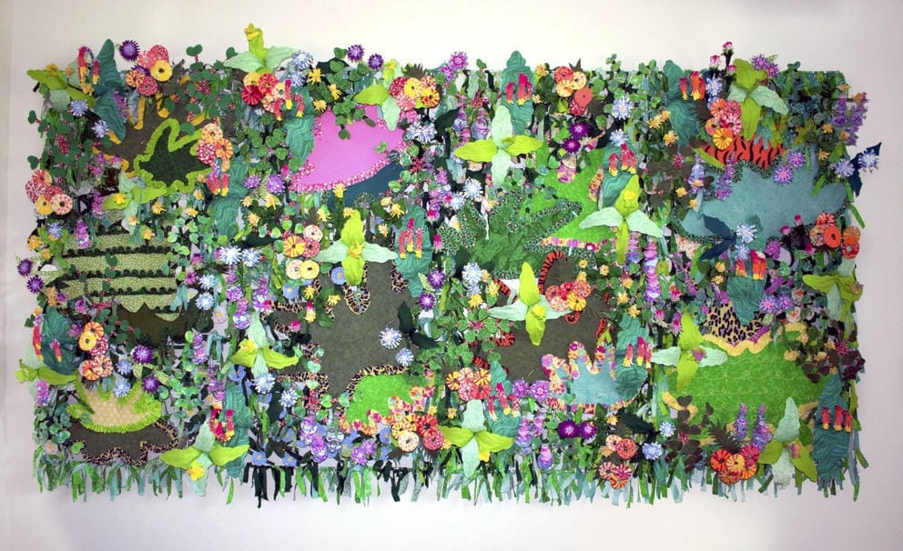 A collage fabric jungle wall with different types and colors of flowers, leaves and greenery as well as patches of animal patterns like tiger stripes and cheetah print.