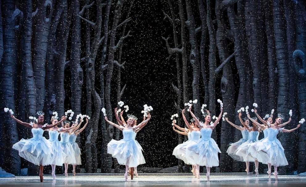 ballerinas in white dresses on a dark backdrop