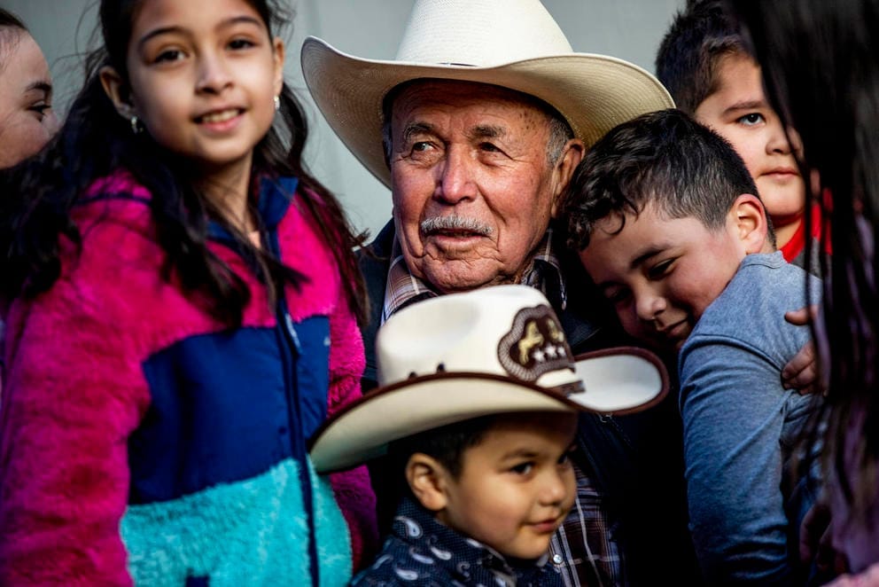 Raul Espinoza Gomez, smiling and wearing a cowboy hat, is surrounded by several of his grand children and great-grandchildren