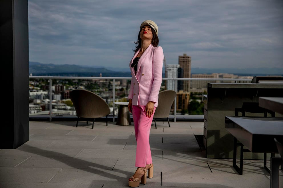 Venus Aoki wearing all pink stands on an outdoor patio with the city in the background