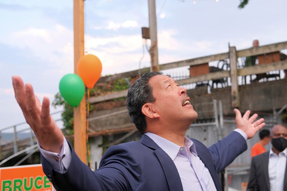 Bruce Harrell gazes up at the sky as it begins to rain with his arms out wide and palms facing up