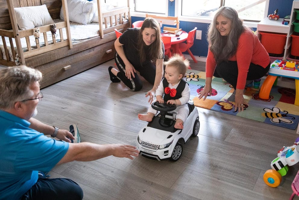 10-month-old Max plays with his mother, Olena Roze, center, and the VanPattens in their home