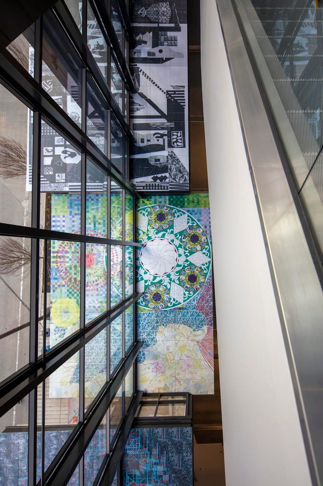 architectural photo featuring a glass wall, three boxes with colorful panels and the siding of an escalator