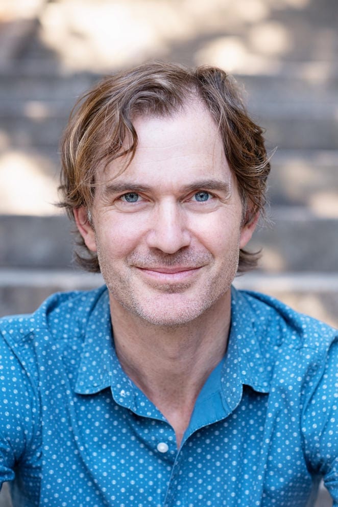 chest-up photo of a man facing the camera and smiling with his mouth closed
