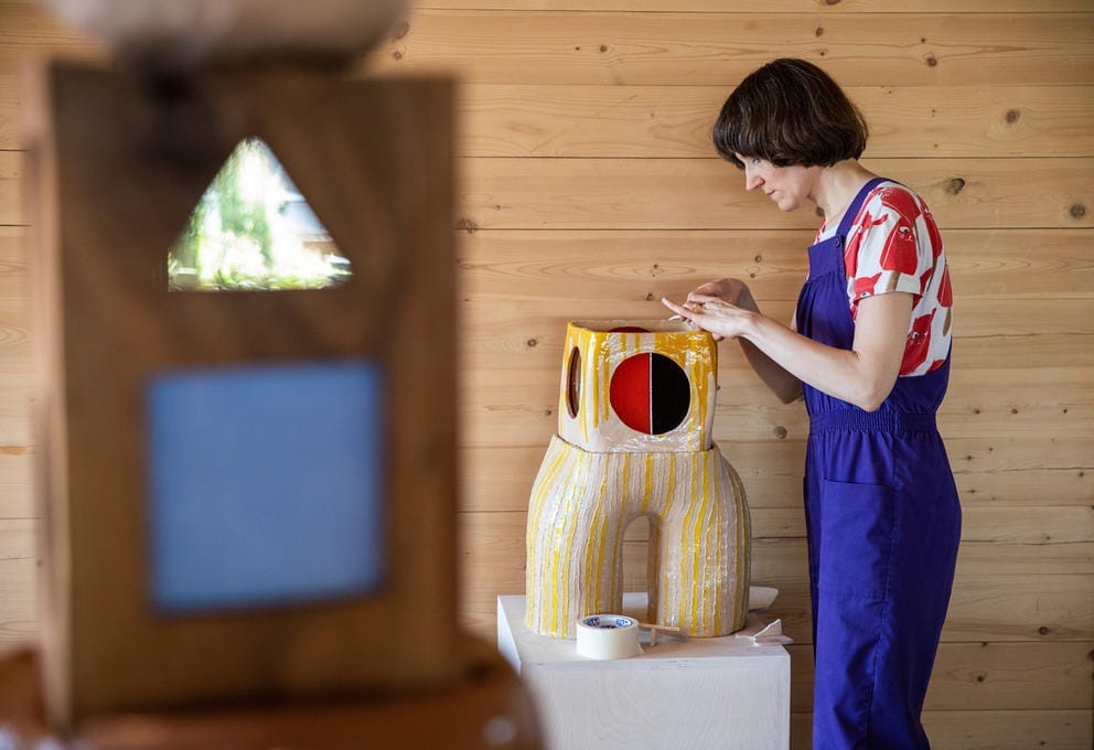 Person in blue overalls works on a sculpture