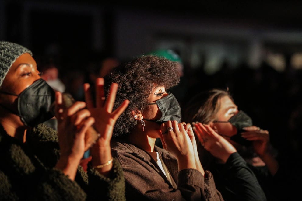 Two people in masks watch a concert