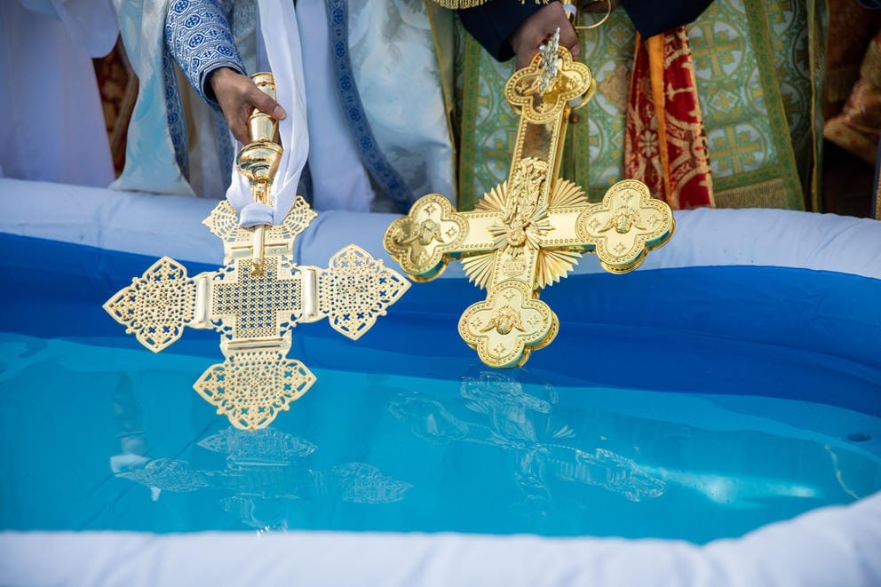 A close up of gold crosses dipping into a pool of water