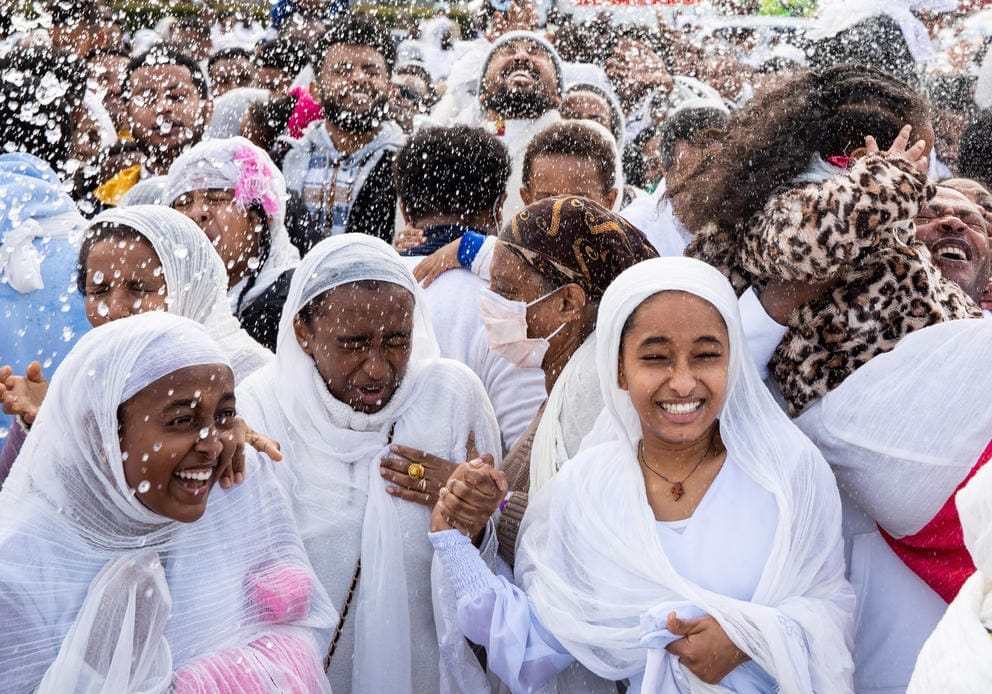 A group of people wearing white are sprayed with water