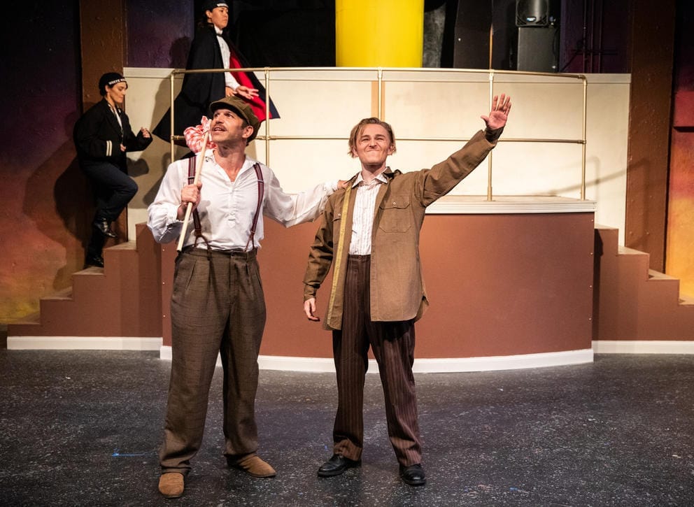 Two people stand on a stage with their hands lifted in the air