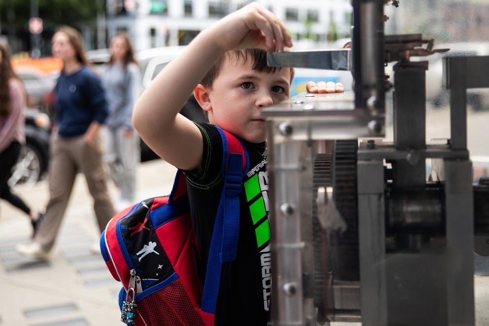A close up of a boy putting a coin into a souvenir machine
