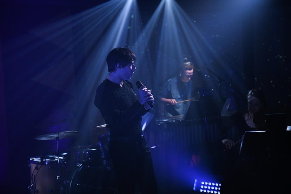 person sings on the stage, blue light envelops him