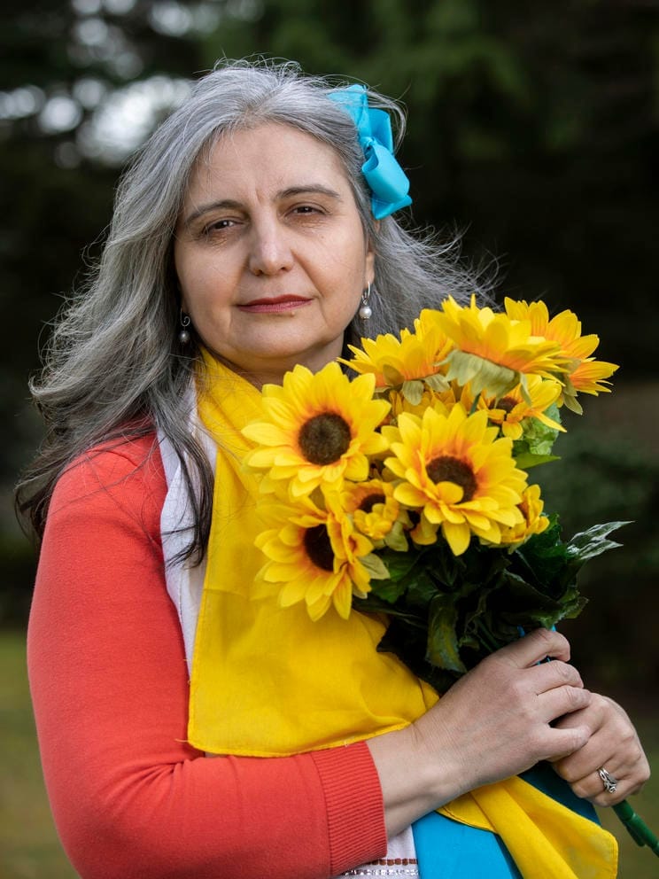 Irina VanPatten is adorned with a special Moldovan hand towel and colors of the Ukrainian flag while holding decorative sunflowers
