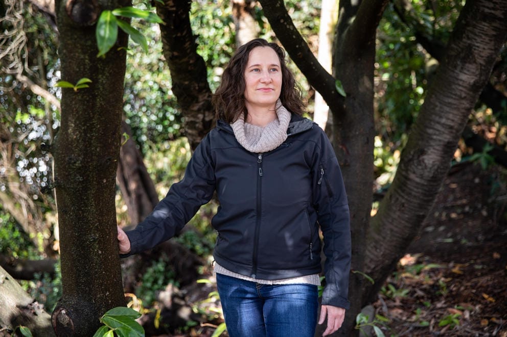 A woman stands between tree branches