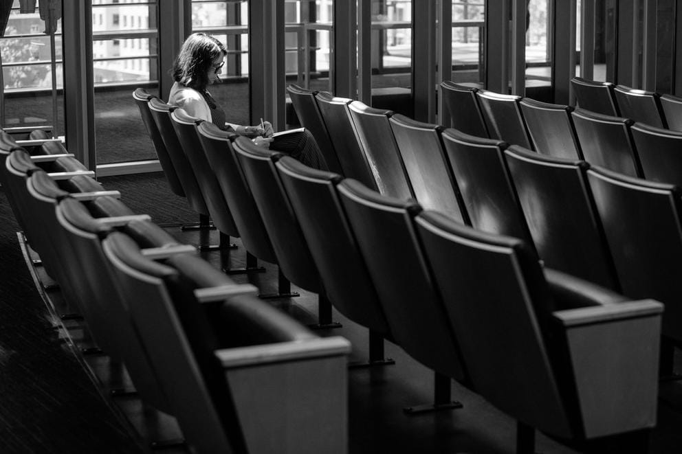 a woman sits in council chambers taking notes