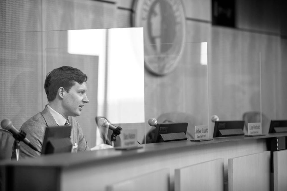 councilmemember andrew lewis sits behind the council dais in city hall