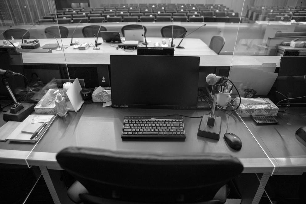 a desk with a computer screen and keyboard sitting behind plexiglass in city hall