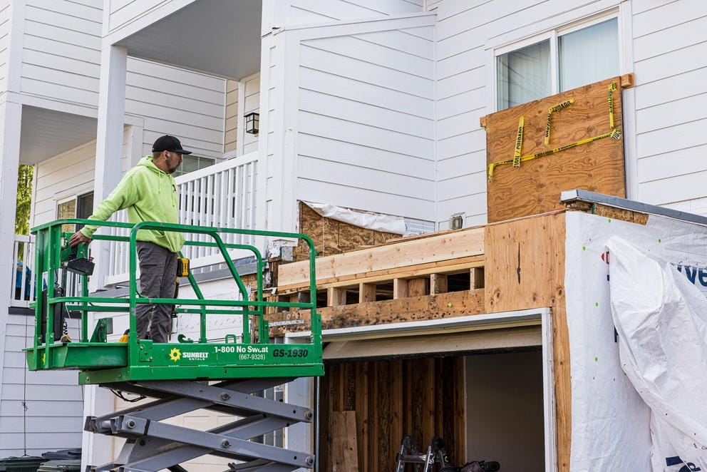 A worker repairs damage to a home from topical mold at JBLM