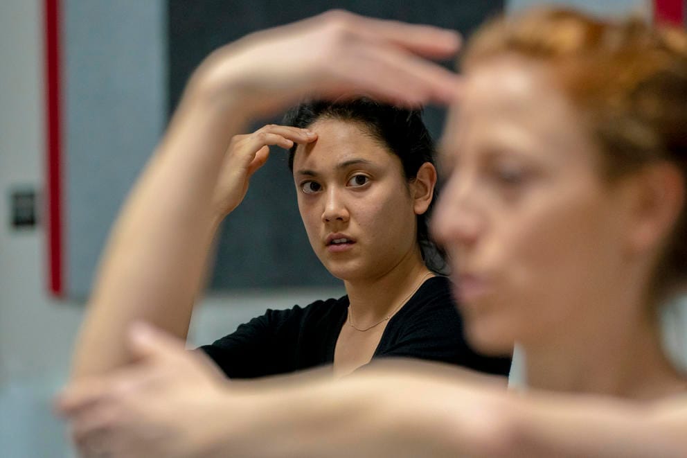 A dancer is seen through the arms of the choreographer as they learn a dance