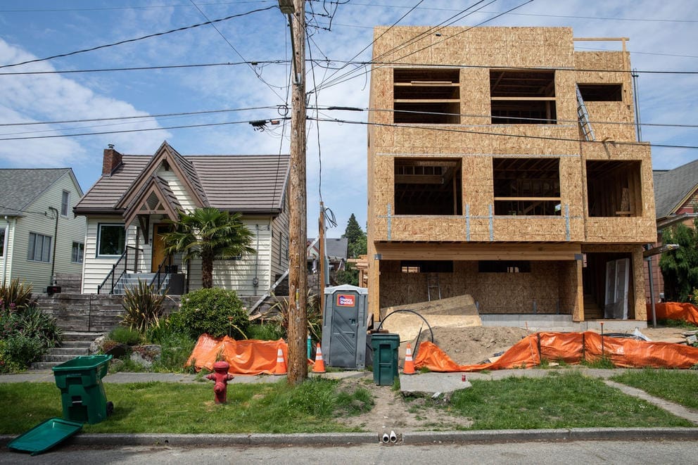 a partially completed townhome next to a single family home