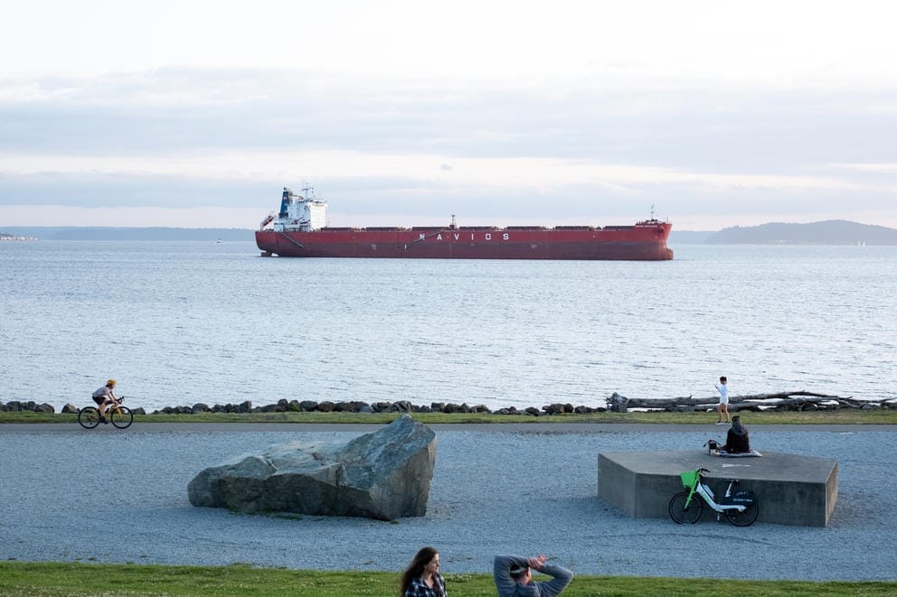 A super wide image of a man biking from the left down a waterfront path