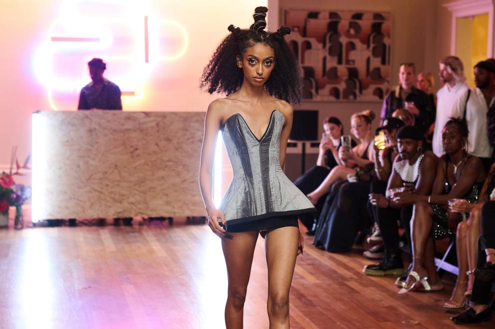 A model in a silver dress walks down the runway