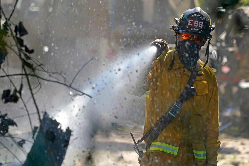 a firefighter sprays a tree with a hose