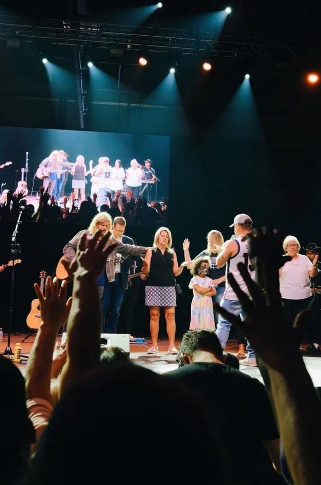 People gather on a stage and pray.