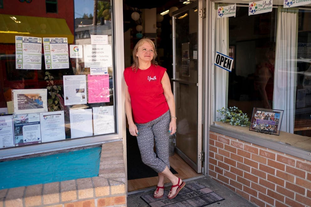 Kirchoff, wearing a red shirt, poses in the storefront doorway of The Youth Connection