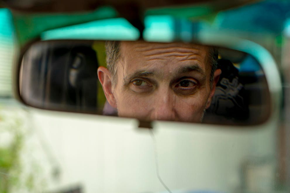 The reflection of a man looking in a rearview mirror