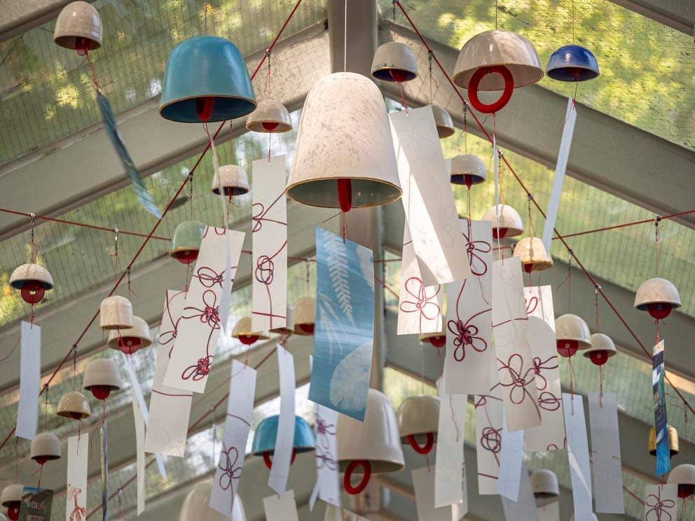 photo of ceramic wind chimes hung outside with red thread