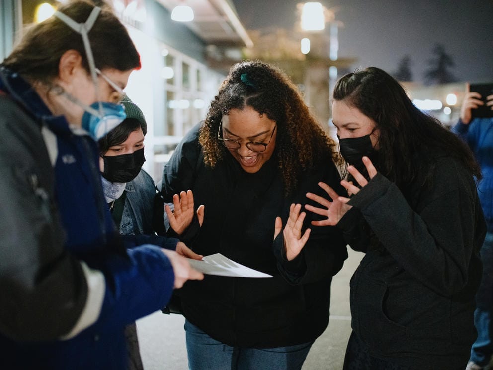 A group excitedly gathers around a sheet of paper