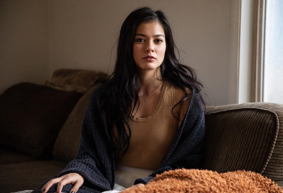A portrait of a woman on a couch next to a window
