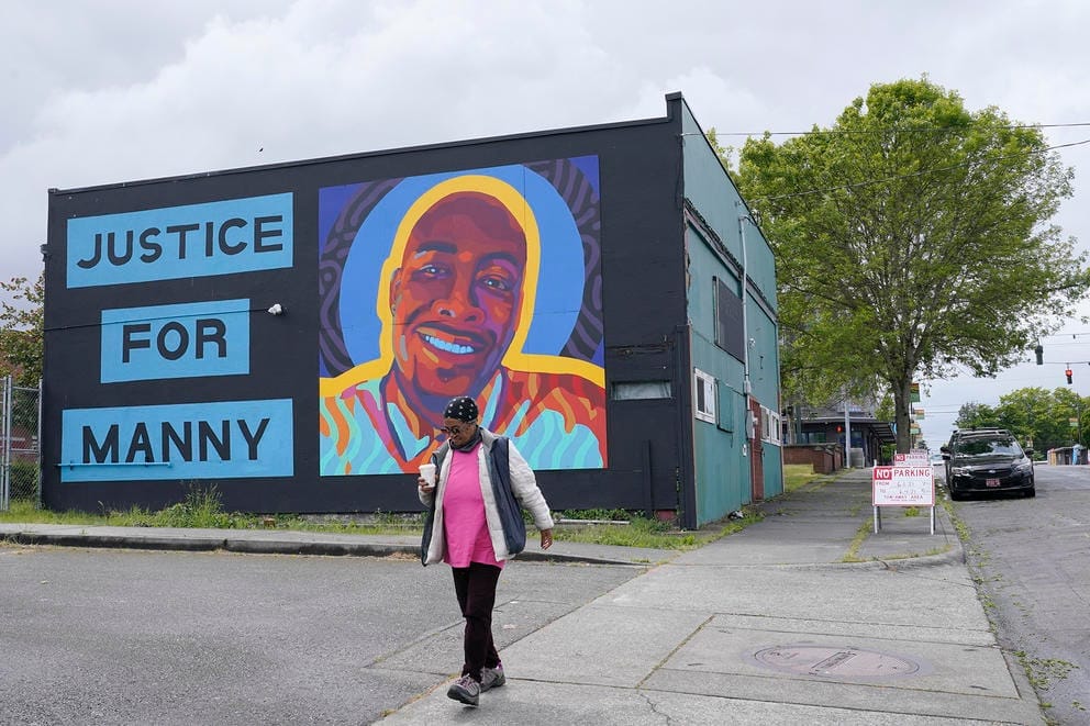 A woman walks past a mural honoring Manuel
