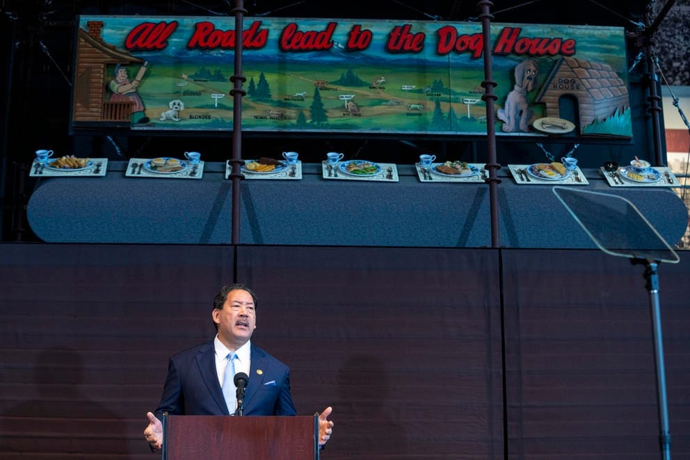 a man stands beneath a sign reading