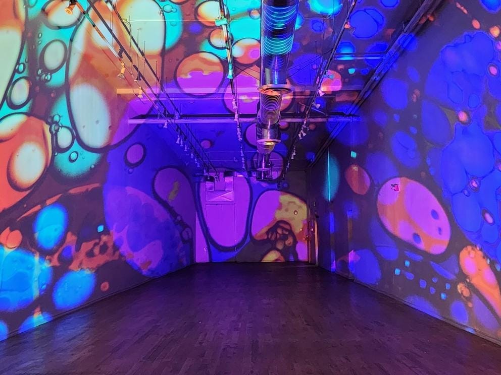 photo of a long empty room lit with lavalamp-like blobs of color