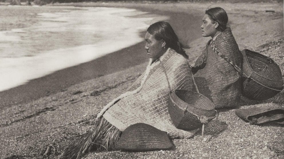 Two Native American on a beach with baskets for clams.
