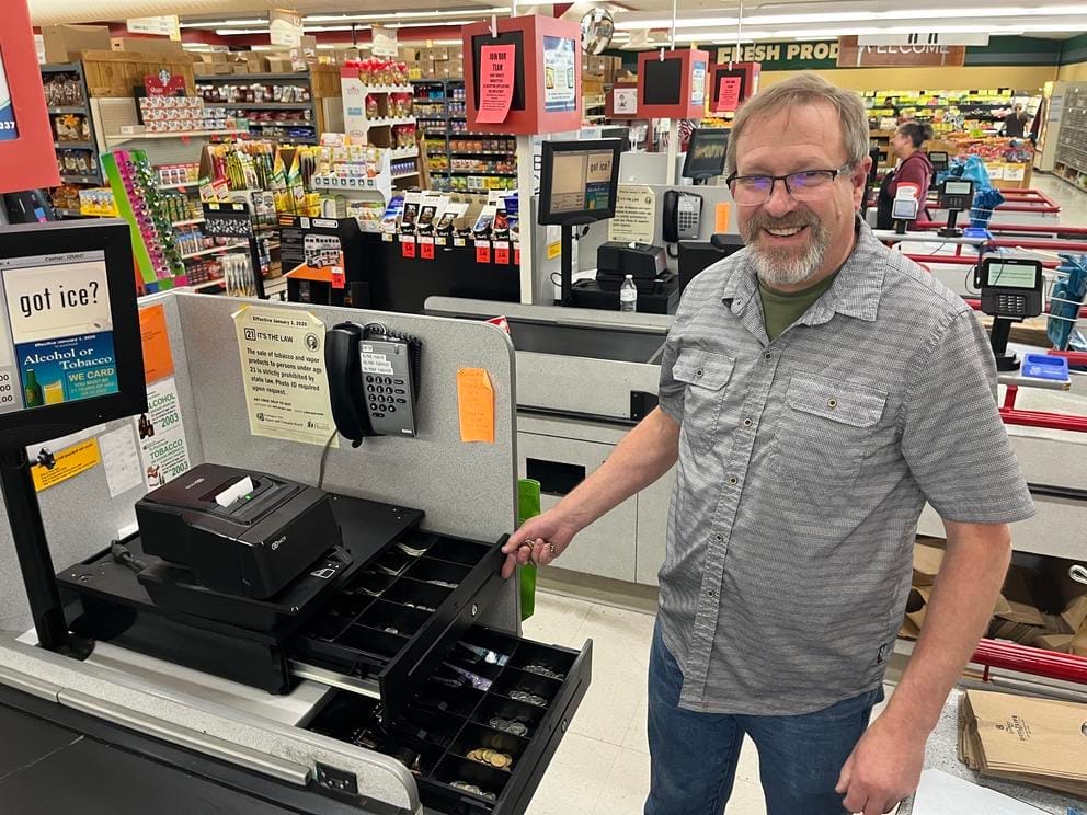 A person stands next to a cash register.