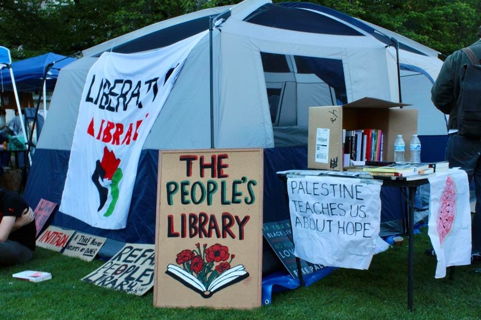 Signs sit outside of the encampment library tent on the University of Washington campus