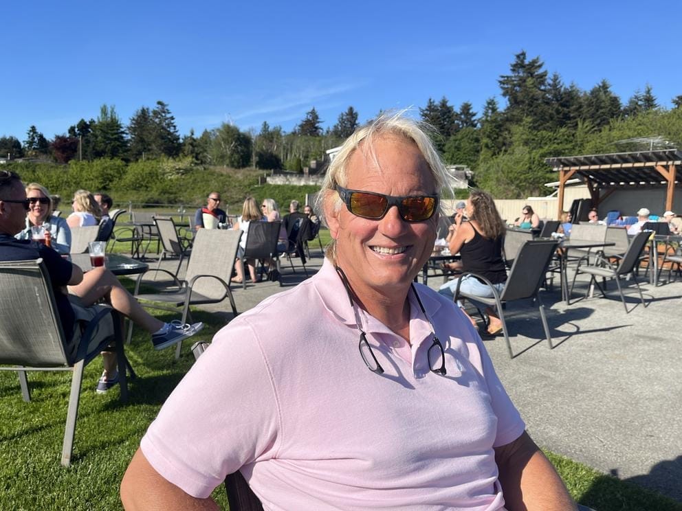 A person wearing sunglasses poses for a photograph in front of a patio