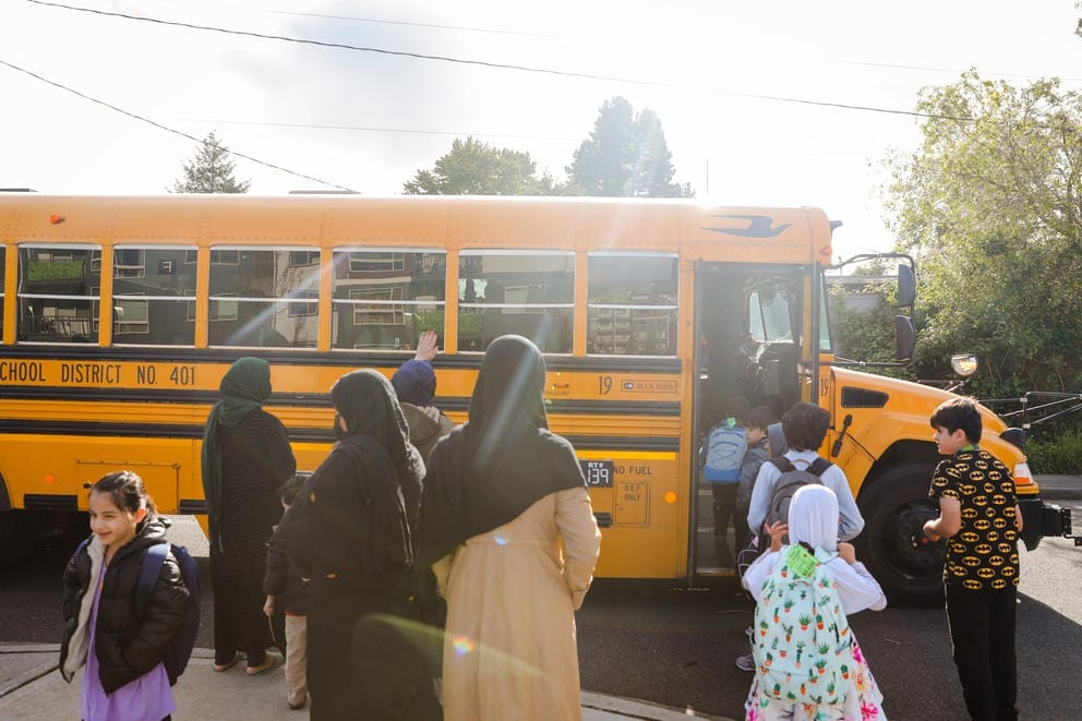 Students get on the bus to Parkside Elementary outside their apartment complex in Des Moines where many immigrant and refugee families live.