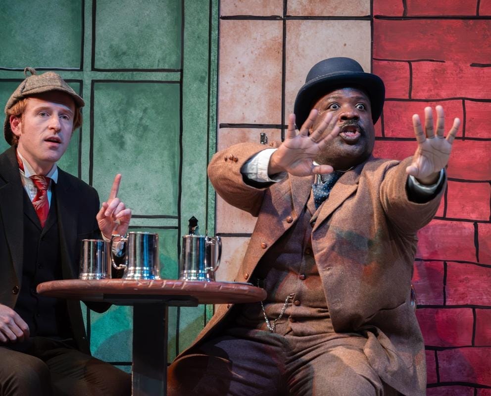 two performers on stage dressed as Sherlock Holmes and Watson
