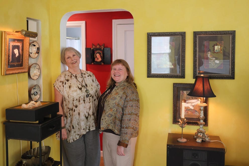 two women pose for a portrait in a living room